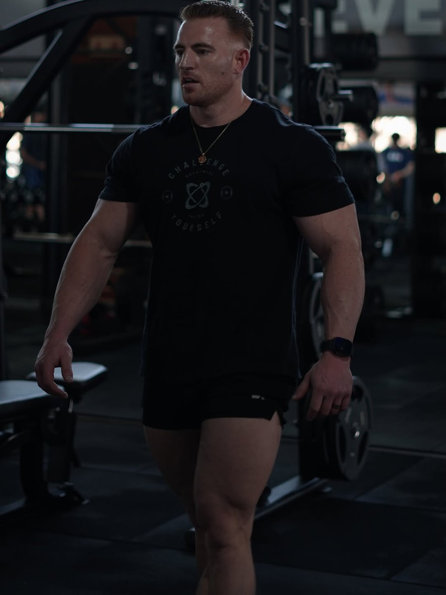 Dylan Dawson carrying a plate across a dark gym floor, 3 of 7