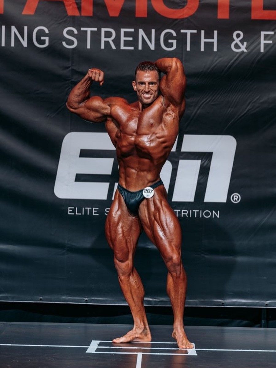 Dylan Dawson on stage at the Euro Muscle Show, front double biceps, 4 of 7